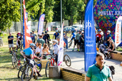 Widok na plac wypełniony osobami w strojach sportowych na rowerach