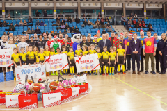 Drużyna koszykarska pozuje do zdjęcia na płycie boiska w towarzystwie dzieci i organizatorów wydarzenia
