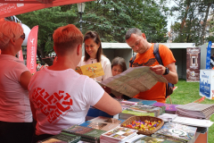 Kobieta i mężczyzna stoją przy stoisku promocyjnym i ogladają mape