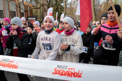 Dzieci w strojach sportowych stoją na linii startu biegu