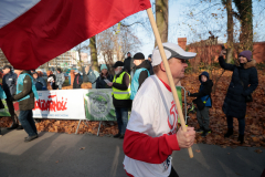 Mężczyzna, uczestnik wydarzenia, biegnie trzymając biało-czerwoną flagę