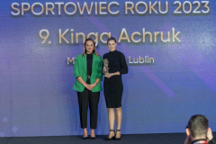 Dwie kobiety stoją na scenie na tle  ekranu z napisem sportowiec roku 2023, jedna z nich trzyma statuetkę
