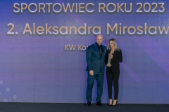 Sportsmenka Aleksandra Mirosław stoi na scenie i prezentuje otrzymaną statuetkę, obok niej stoi mężczyzna