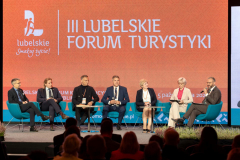 Panel dyskusyjny,  około dziesięciu osób siedzi w fotelach ustawionych na scenie, za nimi znajduje się ekran z napisem III Lubelskie Forum Turystyki