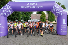 Członek Zarządu Zdzisław Szwed wraz z innymi uczestnikami wyścigu na mecie. Łącznie na zdjęciu widać kilkadziesiąt osób w strojach kolarskich i z rowerami.