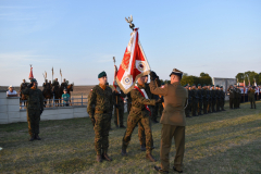 Ceremoniał wojskowy przekazania chorągwi,  jeden z żołnierzy przekazuje chorągiew dwóm pozostałym