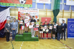 Dziesięcioro dzieci w wieku szkolnym znajduje się na sali gimnastycznej i prezentuje zdobyte dyplomy w konkursie sportowym