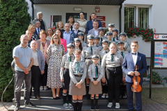 Na schodach przed budynkiem w kilku rzędach stoi około trzydziestu osób, w różnym wieku łącznie z harcerzami, są to uczestnicy odsłonięcia tablicy pamięci