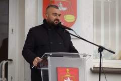 Członek Zarządu Jarosław Kwasek przemawiający z mównicy do zebranych na wydarzeniu. Za nim, na ścianie, widoczny jest herb Gminy Firlej - przedstawiający na tarczy w polu czerwonym złotą wagę zakończoną uchwytem w kształcie rombu i krzyżem, pomiędzy odważnikami srebrną łódź z wioślarzem, natomiast pod nią srebrną sześcioramienną gwiazdę.