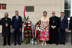 Członkowie wydarzenia stojący przed nowo odsłoniętą tablicą. Bezpośrednio pod tablicą znajdują się dwa wieńce kwiatowe oraz po dwa znicze. Wśród zgromadzonych są, między innymi, Profesor Sabina Bober, Ksiądz Biskup Mieczysław Cisło, Rabin Symcha Keller oraz Burmistrz Karol Ługowski.