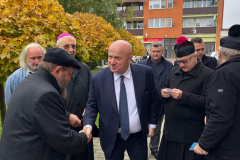Marszałek Stawiarski, otoczony członkami Kościoła, wymieniający się uściskiem dłoni z Rabinem Symchą Kellerem.