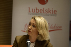Anna Kalczyńska, dziennikarka,  udziela wypowiedzi do mikrofonu, za nią znajduje się roll up z napisem Lubelskie Warto być Polakiem