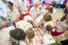 Kilkunastu młodych zawodników sportowych podczas podpisywania koszulek