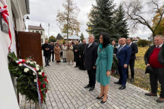 Sekretarz WL i profesor Sabina Bober, stoją przed ścianą budynku na którym zostałap owieszona tablica pamięci i wspólnie z innym izebranymi oddają hołd pomordowanym