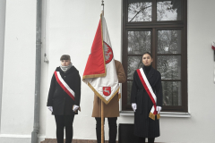 Młodzieżowy poczet sztandarowy stoi przed budynkiem podczas wydarzenia