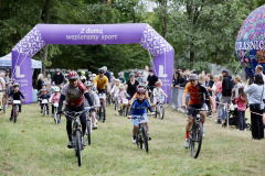 Rowerzyści odjeżdżają z linii startu wyznaczonej nadmuchiwaną bramą.