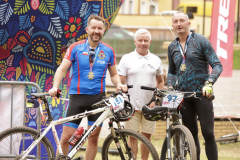 Rowerzyści odznaczeni medalami pozujący wraz ze swoimi rowerami oraz jednym z organizatorów.