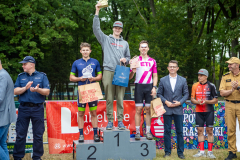 Trójka uczestników maratonu prezentujących swoje nagrody na podium.