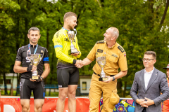 Zdjęcie przedstawia trzech gratulujących sobie mężczyzn z pucharami w dłoniach stojących na podium.