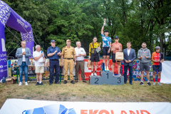 Trzy kobiety na podium pokazują swoje puchary oraz nagrody. Są w towarzystwie organizatorów maratonu.