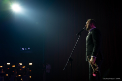 Artysta podczas występu, młody mężczyzna śpiewa piosenkę, trzyma w ręku trąbkę