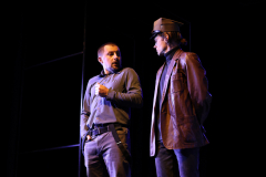Dwóch aktorów stoi na scenie i rozmawiają ze sobą podczas wystepu scenicznego