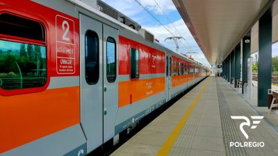 Pociąg stojący na stacji. W prawym dolnym rogu zdjęcia widoczny jest logotyp firmy POLREGIO.
