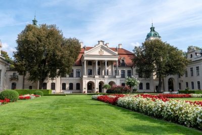 Stary budynek należący do rodziny Zamoyskich stojący pośród bujnych ogrodów oraz kwitnących roślin.